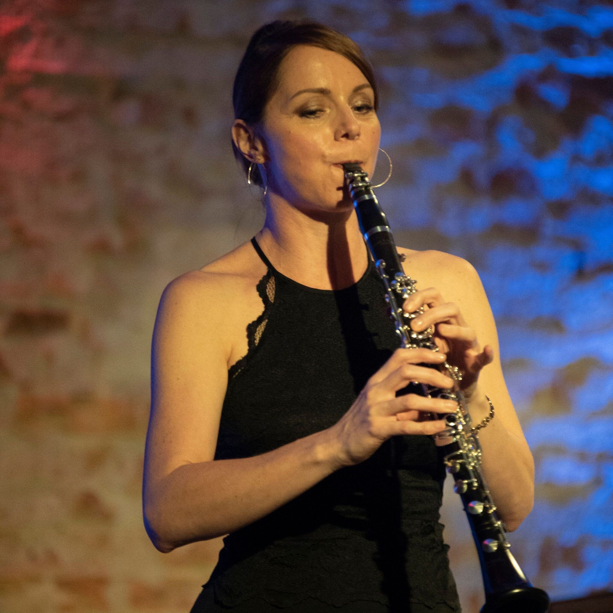 Frau spielt Klarinette in einem schwarzen Kleid